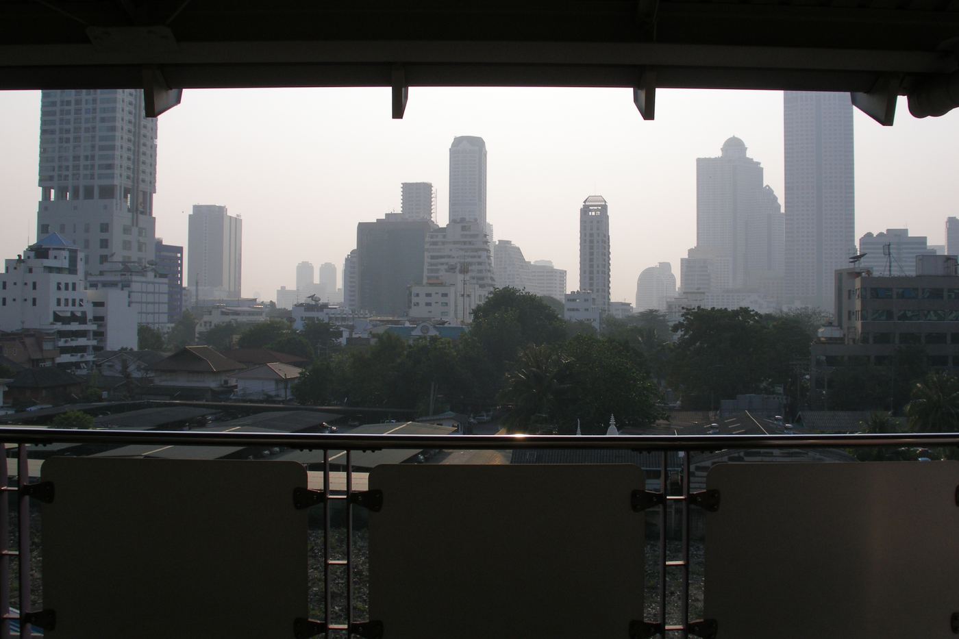 The Bangkok skyline under a hazy sky, with high-rise towers along the horizon