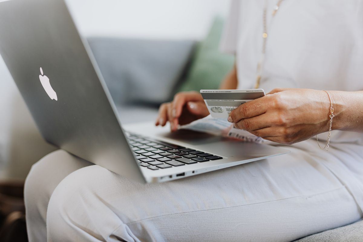 A person reviewing a payment card on a laptop while organising household finances