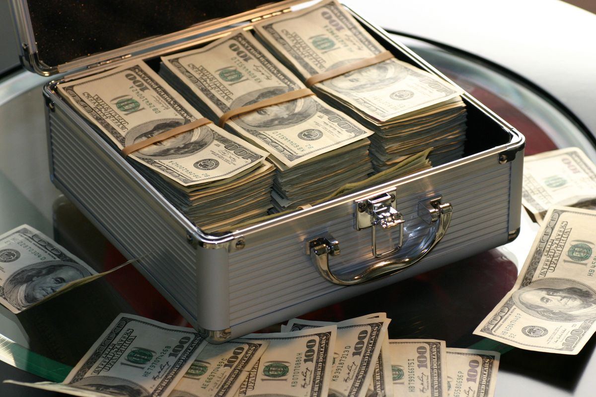 An open briefcase containing stacked bundles of banknotes, representing accumulated savings